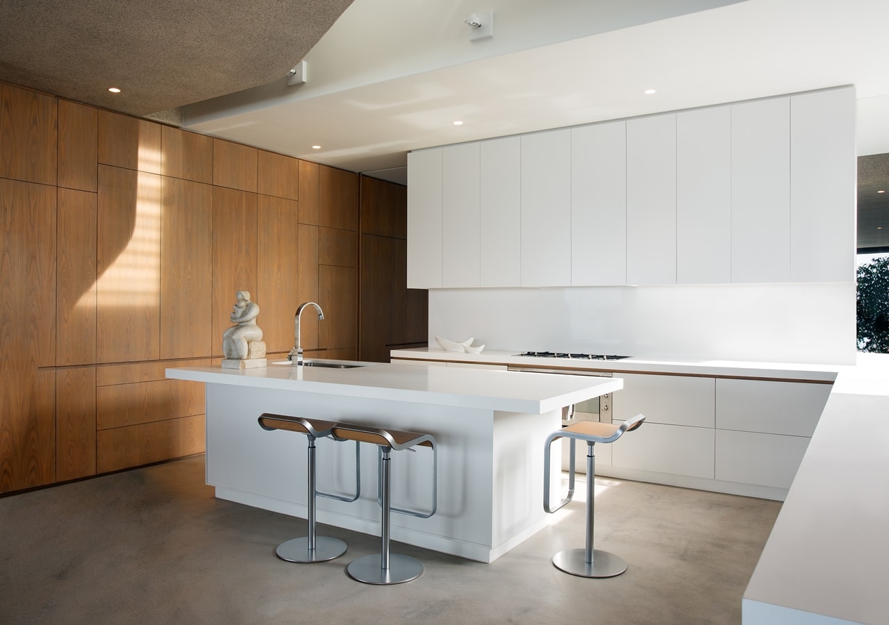 White kitchen in modern home with wooden facade by SAOTA
