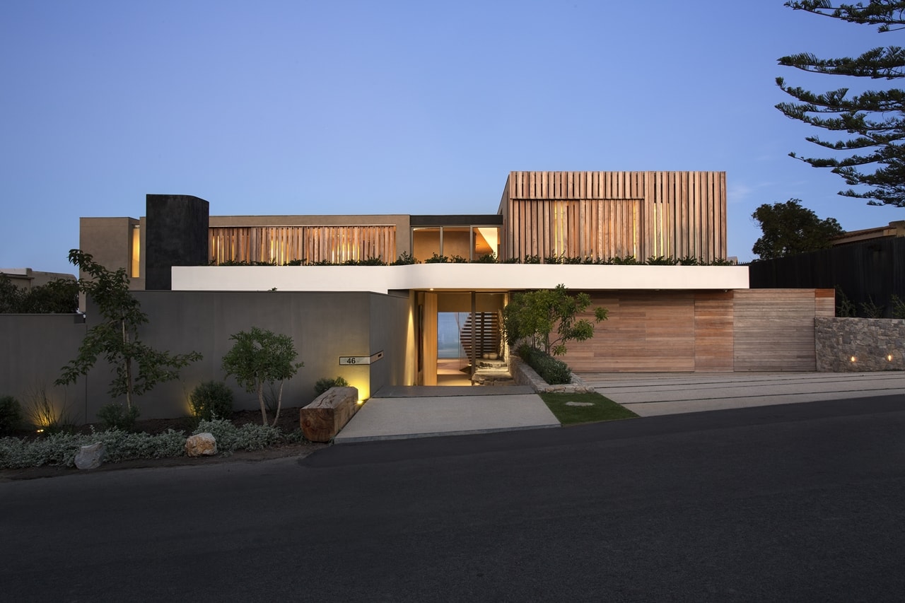 Front view of modern home with wooden facade by SAOTA at night