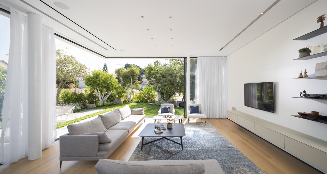 Living room with sliding glass wall in modern LB house by Shachar Rozenfeld Architects