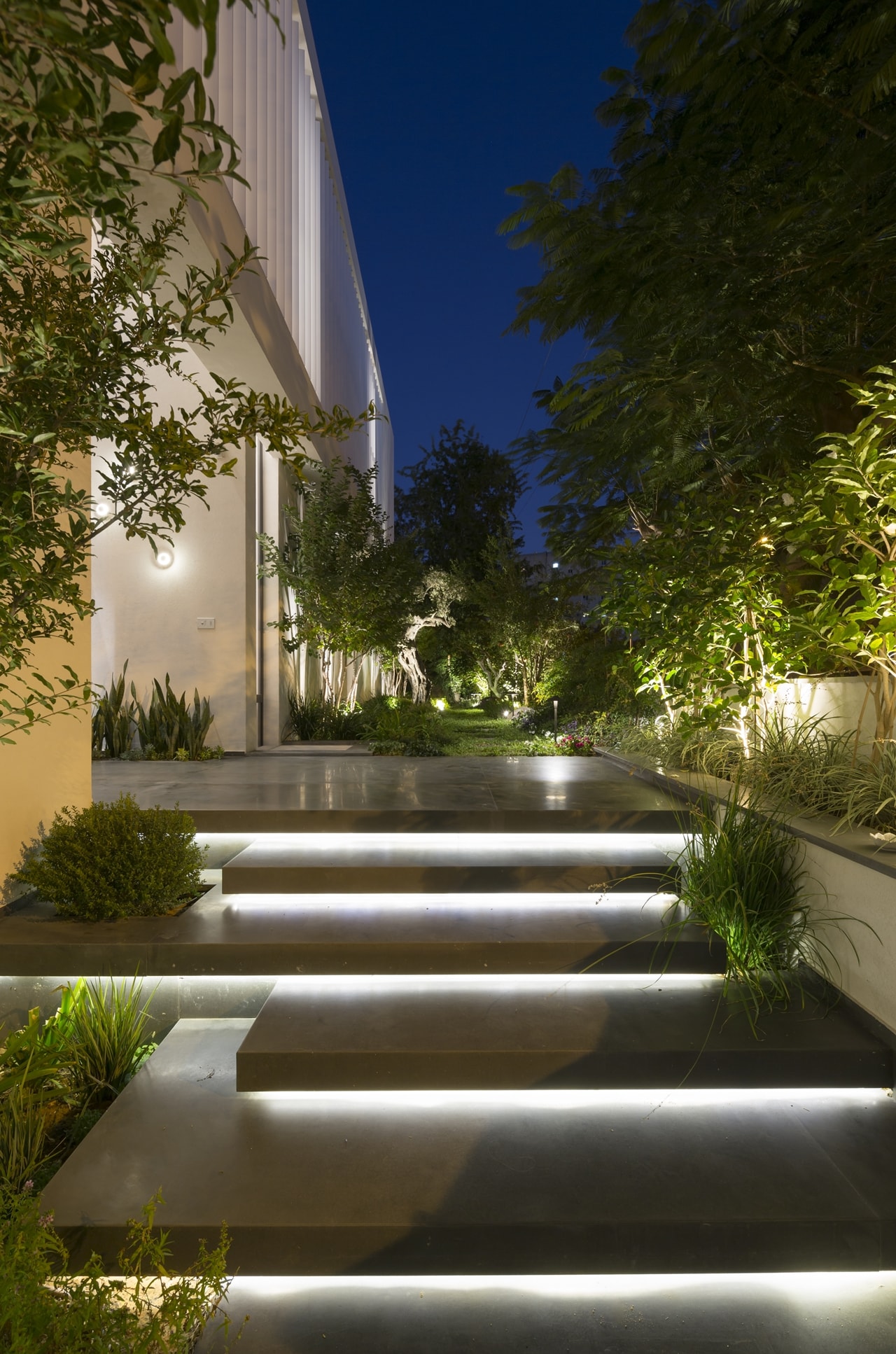 Entrance staircase lit up at night in modern LB house by Shachar Rozenfeld Architects