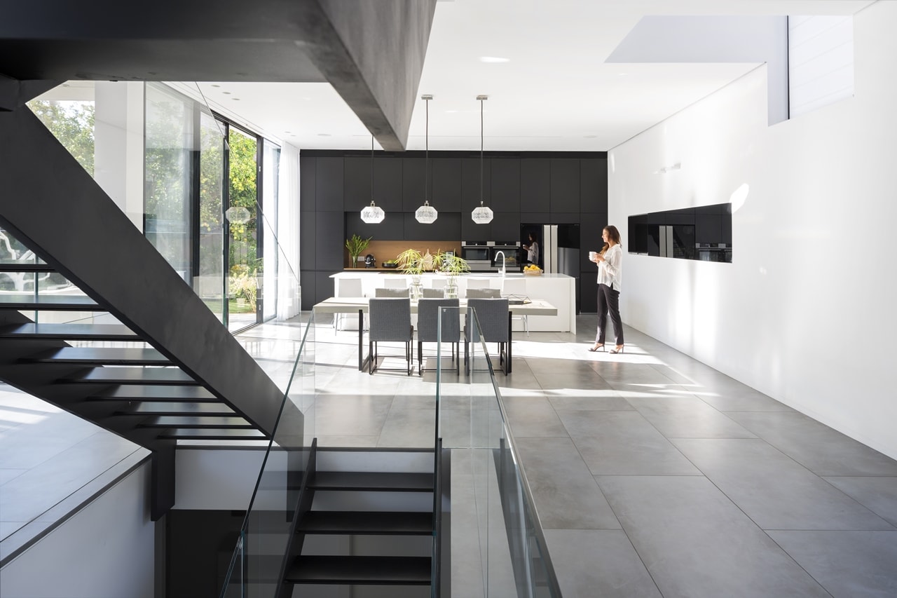 Floating stairs with dining room and black and white kitchen in the background