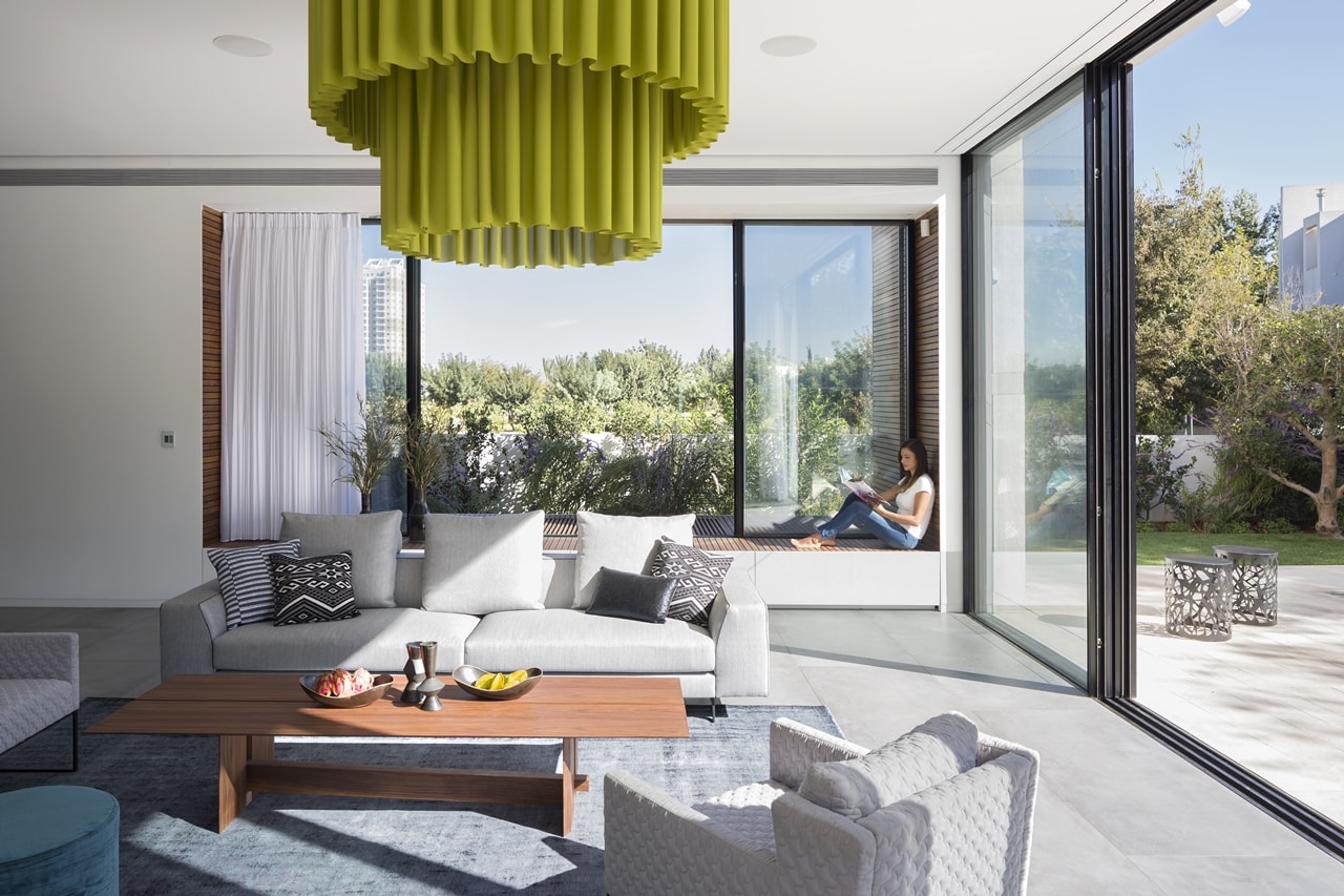 Living room with sliding glass doors in simple modern home by Sachar-Rozenfeld Architects