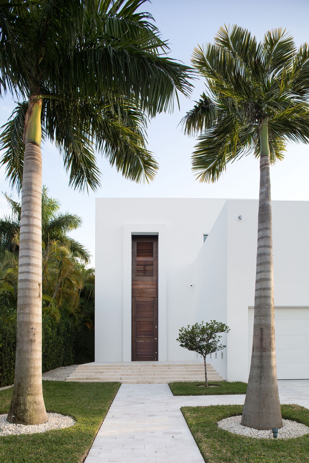 White brick walkway passing between two palm trees