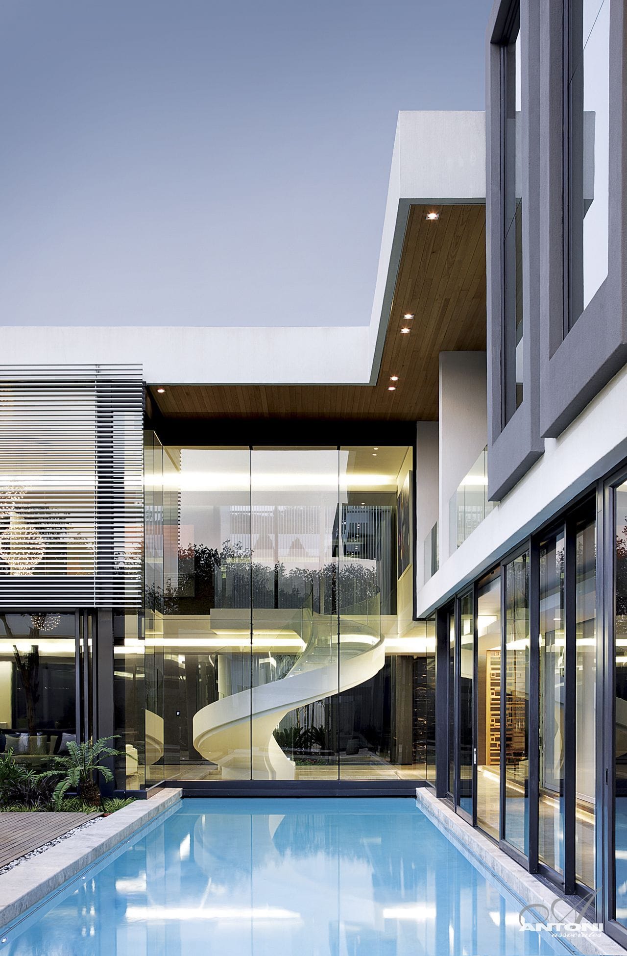 Modern spiral staircase by the glass wall, designed by Antoni Associates